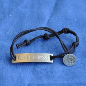 armband i textil med epilepsimärket på silvrig knapp och texten epilepsi på silverfärgad metallplatta